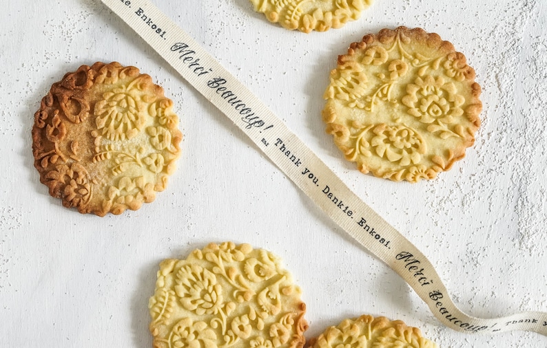 Several well baked cookies with polish folk traditional design are on the white background. A cotton ribbon with "thank you" text in different languages is going across the photo.