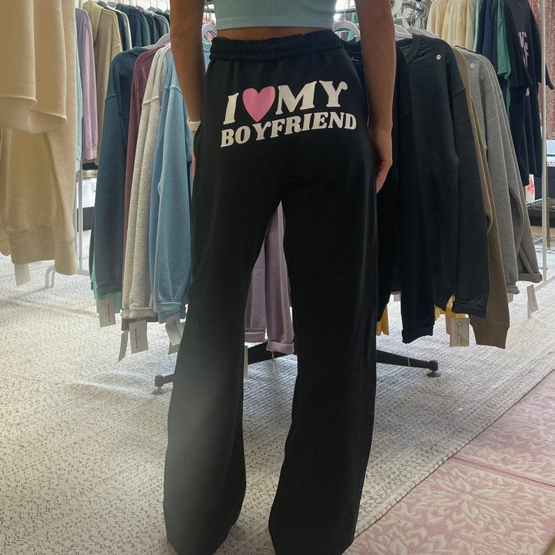 May include: Black sweatpants with a white graphic that says "I love my boyfriend" with a pink heart.
