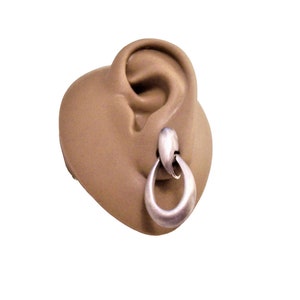 May include: Silver hoop earrings with a unique twisted design. The earrings are shown on a mannequin ear.