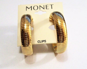 May include: Gold-toned Monet clip-on earrings with a ribbed design. The earrings are displayed on a white card with the word "MONET" and "CLIPS" printed on it.