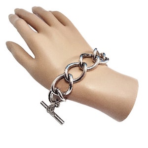 May include: A silver chain bracelet with a toggle clasp. The bracelet is made of thick, linked chains.