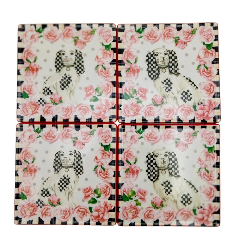 May include: A set of four square coasters featuring a central illustration of a white dog with black and white checkered ears and spots. The dog is surrounded by a border of pink roses on a white background with grey polka dots and black stripes.
