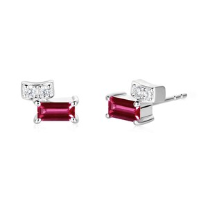 May include: A pair of silver stud earrings. Each earring features a rectangular, deep pink gemstone and a small, curved section with three clear gemstones. The earrings are set against a white background.