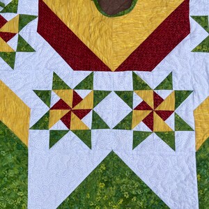 May include: A Christmas tree skirt with a white background and a pattern of green, red, and yellow stars. The skirt has a scalloped edge.
