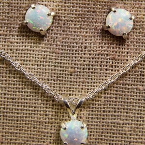 May include: A silver chain necklace with a white opal pendant and a pair of matching opal earrings.