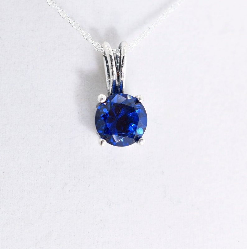 May include: A silver necklace with a blue gemstone pendant.