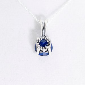 May include: A silver necklace with a blue gemstone pendant. The pendant has a detailed silver setting.