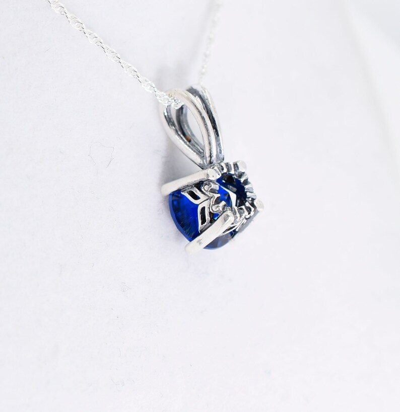 May include: A silver necklace with a blue gemstone pendant. The pendant is set in a silver frame with intricate details.