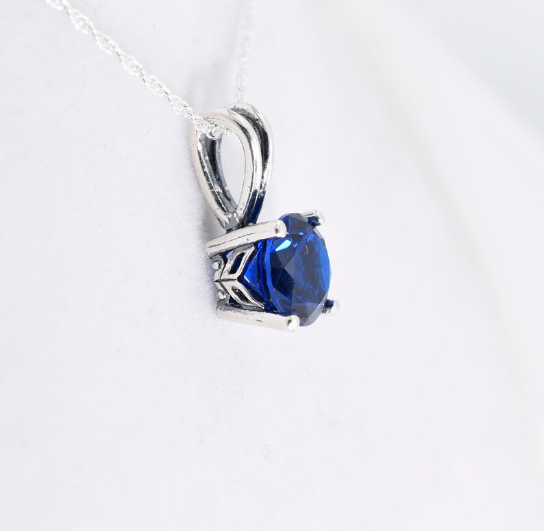 May include: A silver pendant necklace with a blue gemstone set in a silver bezel setting.