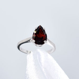 May include: A silver ring with a pear-shaped red gemstone.