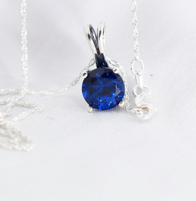 May include: A silver necklace with a large, round, blue gemstone pendant.