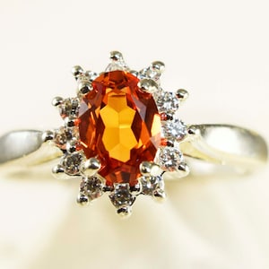 Padparadscha Sapphire Ring, 7 by 5mm Faceted Oval Gemstone .80ct Set in 925 Sterling Silver Ring With Halo of Cubic Zirconia
