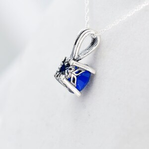 May include: A silver pendant necklace with a blue gemstone set in a detailed silver frame. The pendant is attached to a silver chain.