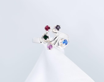 Puede incluir: Anillo de plata con un diseño de espiral y cinco piedras preciosas de colores: rojo, verde, morado, rosa y azul.
