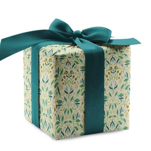 May include: A square gift box wrapped in cream paper with a green and yellow floral pattern. The box is tied with a teal blue ribbon.