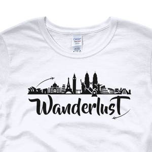 May include: White women's t-shirt with a black silhouette of a city skyline and the word "Wanderlust" in black script.