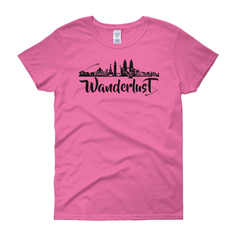 May include: Pink women's t-shirt with a black silhouette of a city skyline and the word "Wanderlust" in black script.