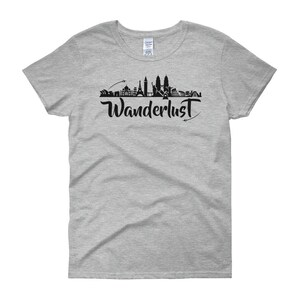 May include: A heather grey women's t-shirt with a black silhouette of a city skyline and the word "Wanderlust" in black script.