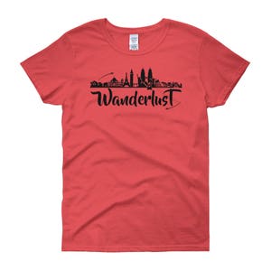 May include: Red women's t-shirt with a black silhouette of a city skyline and the word "Wanderlust" in black script.