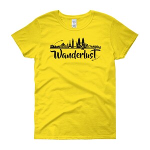 May include: Yellow women's t-shirt with a black silhouette of a city skyline and the word "Wanderlust" in black script.