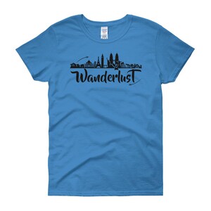 May include: A light blue women's t-shirt with a black silhouette of a city skyline and the word "Wanderlust" in a stylized font.