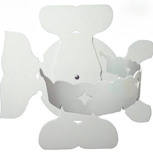 May include: White paper cupcake liner with a scalloped edge and a star-shaped cutout. The liner is folded into a butterfly shape.