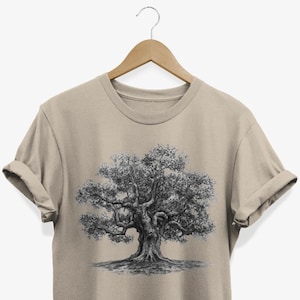 Könnte beinhalten: Ein beiges T-Shirt mit einer schwarz-weißen Zeichnung eines großen Baumes auf der Vorderseite.