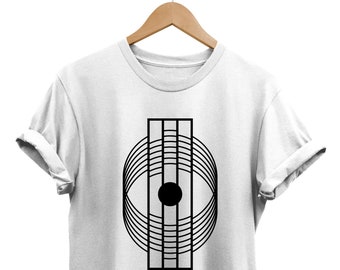 May include: White t-shirt with a black geometric design featuring a circle with concentric lines and a black dot in the center.