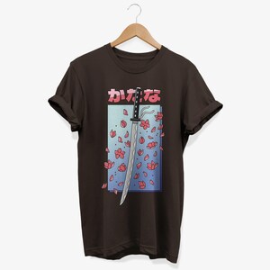 May include: A brown t-shirt featuring a graphic of a katana sword with pink cherry blossoms falling around it. The Japanese text on the shirt reads "かなな".