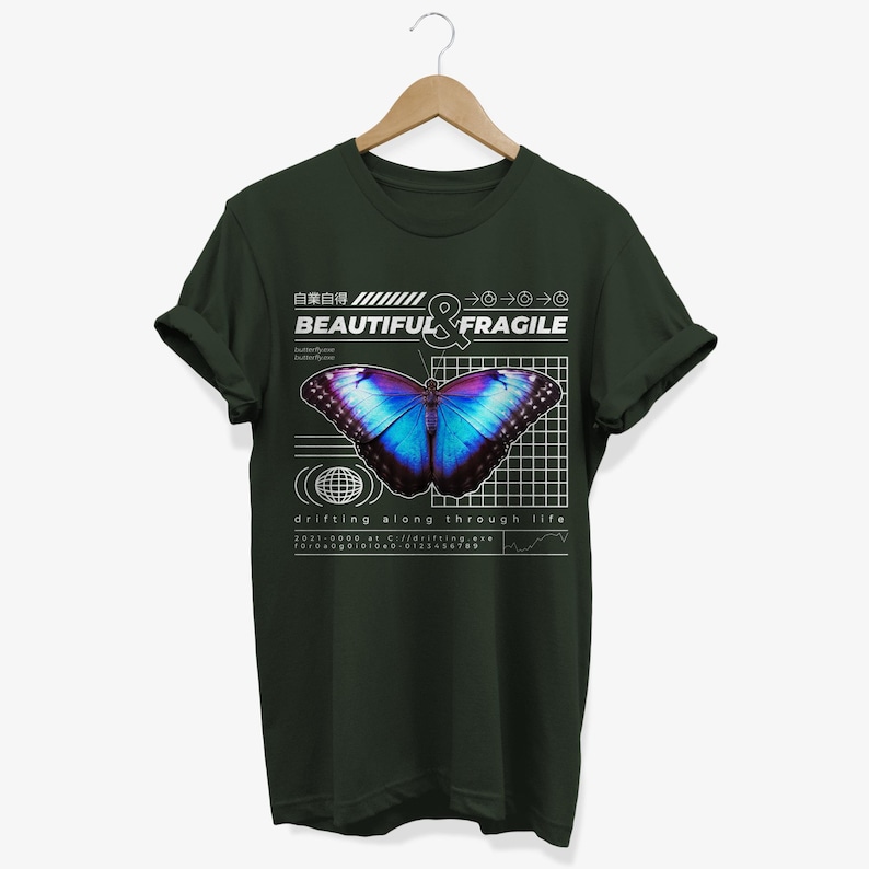 May include: A dark green t-shirt with a graphic design featuring a blue and purple butterfly with the text "BEAUTIFUL & FRAGILE" and "drifting along through life".