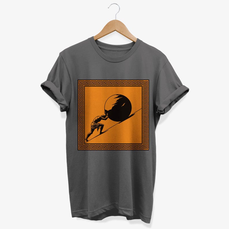 May include: A dark gray t-shirt with a graphic of a person pushing a large stone uphill. The graphic is framed by a square border with a repeating Greek key pattern in orange. The background of the graphic is orange.