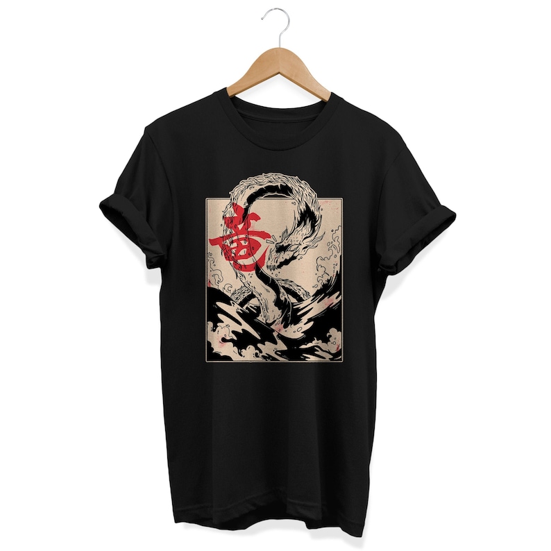 Puede incluir: Camiseta negra con un estampado gr&aacute;fico de un drag&oacute;n blanco y negro en una ola con caracteres japoneses rojos.