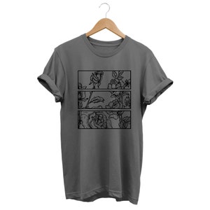 May include: A gray t-shirt with a floral design. The design features black line art of roses and leaves arranged in three horizontal rectangular panels. The shirt is hanging on a wooden hanger.