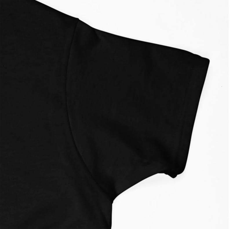 May include: Close-up of the black short sleeve of a t-shirt. The fabric is smooth and appears to be made of cotton.