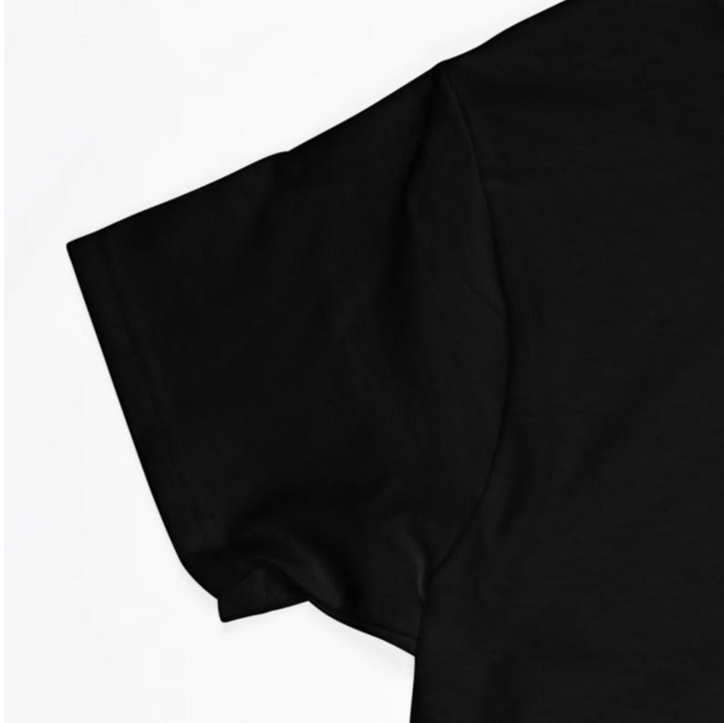 May include: Close-up of the black short sleeve of a t-shirt. The fabric is smooth and appears to be made of cotton.