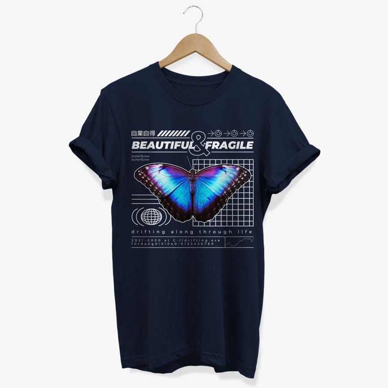 May include: Navy blue t-shirt with a graphic of a blue and purple butterfly on a grid pattern. The text "BEAUTIFUL & FRAGILE" is above the butterfly. The text "drifting along through life" is below the butterfly.