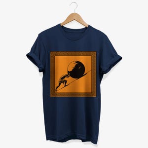 May include: A navy blue t-shirt with a graphic of a person pushing a large stone uphill. The graphic is surrounded by a gold Greek key border.