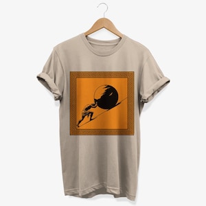 May include: A beige t-shirt with a graphic of a person pushing a large stone uphill. The graphic is framed by a black and orange Greek key pattern.
