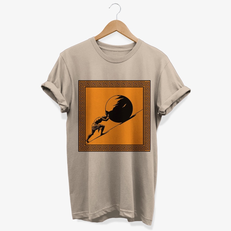 May include: A beige t-shirt with a graphic of a person pushing a large stone uphill. The graphic is framed by a black and orange Greek key pattern.