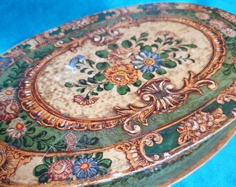 May include: Oval-shaped wooden box with a green and gold painted design. The box is decorated with floral motifs and intricate scrollwork.