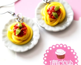 May include: A pair of earrings featuring miniature plates with spaghetti and tomato sauce. The plates are white with a scalloped edge. The earrings are made of silver and have a hook closure.