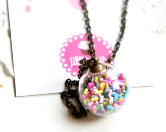 May include: A gold chain necklace with a clear glass orb pendant filled with colorful sprinkles.