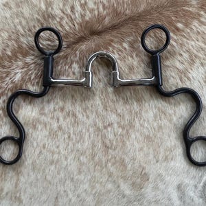 May include: A black and silver horse bit with a curved mouthpiece and two rings on each side.
