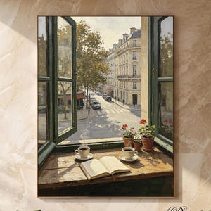 Puede incluir: Un cuadro decorativo que muestra una ventana abierta con vistas a una calle urbana con edificios y árboles. En el alféizar de madera hay un libro abierto, dos tazas de café blancas sobre platillos y dos macetas de terracota con flores rojas.