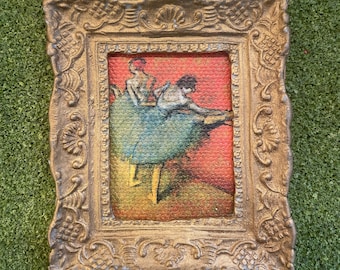 May include: A framed painting of two dancers in a ballet pose. The dancers are wearing blue and white costumes and are set against a red background. The frame is gold and ornate.