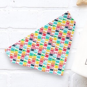 May include: A white bandana with a colorful repeating pattern of the text "It's My Birthday".