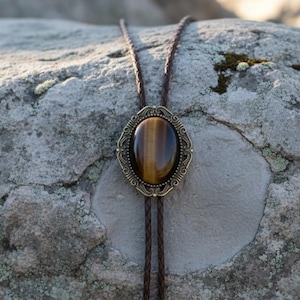 Tiger’s eye bolo tie on a rustic rock.