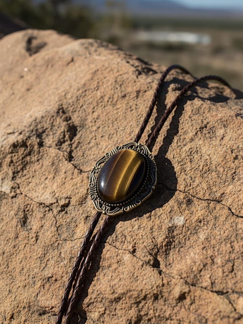 Tiger’s Eye bolo tie draped on a rock.