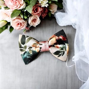 May include: A floral patterned bow tie with a beige background and green, pink, and orange flowers.