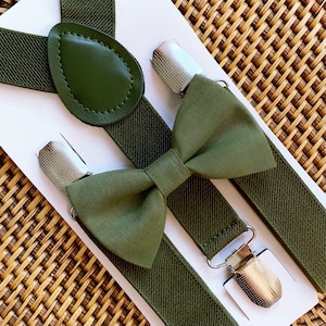 Olive green bow tie and suspenders on wicker tray.